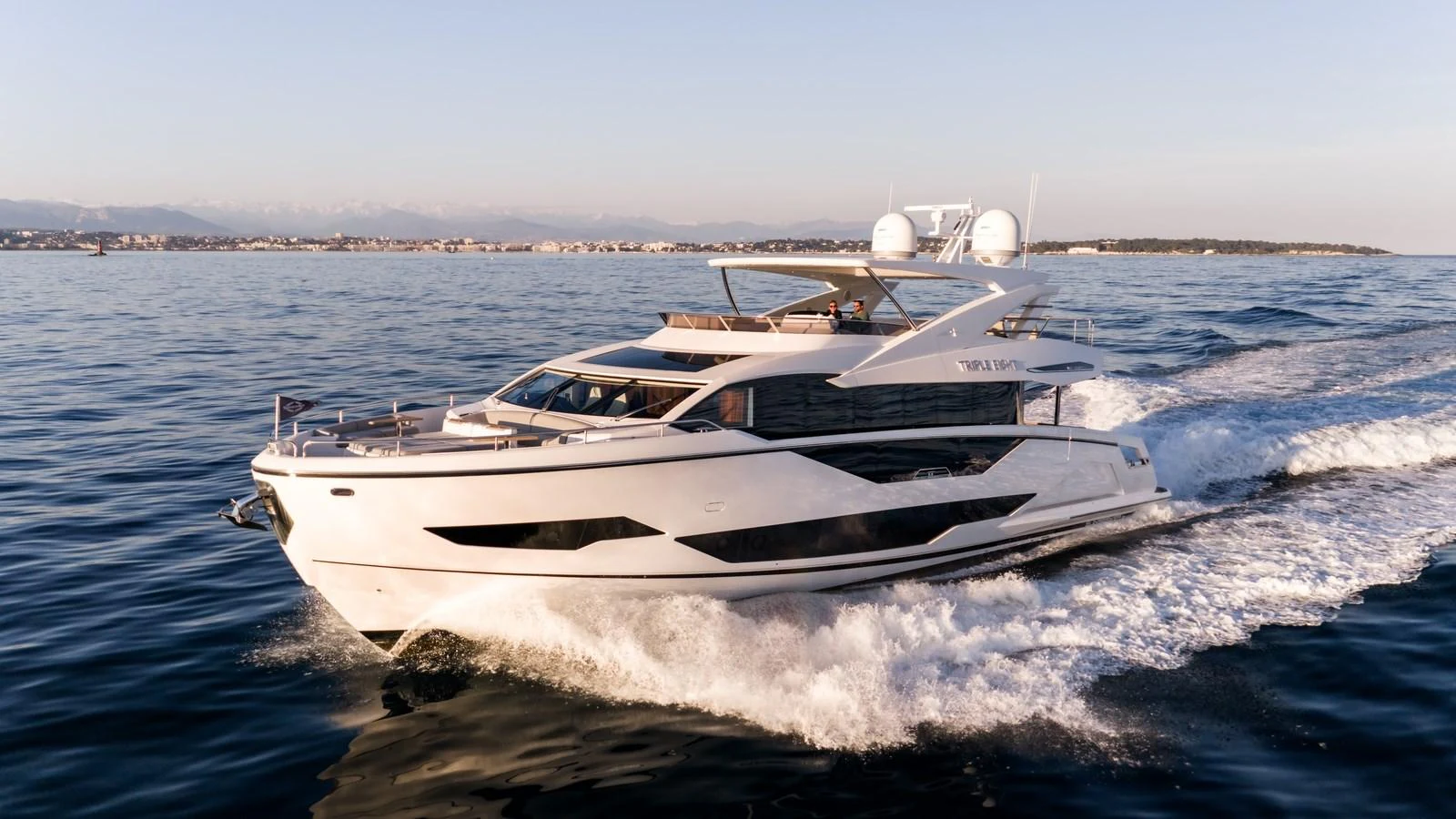 A sleek yacht cruises through the water at sunset, showcasing its modern design and luxurious amenities. aboard TRIPLE EIGHT Yacht for Sale