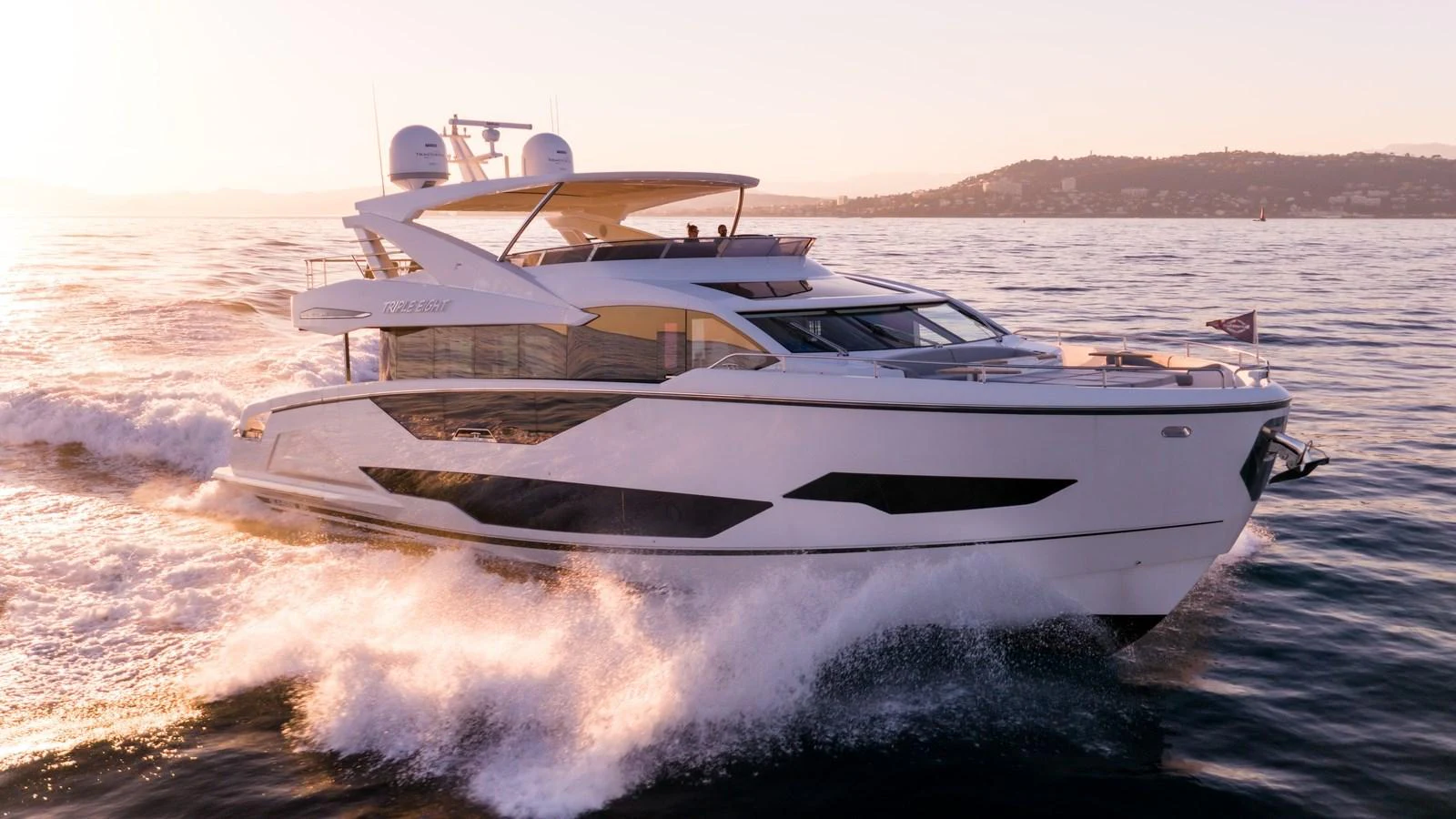 A sleek and modern yacht cruises swiftly through the water at sunset. aboard TRIPLE EIGHT Yacht for Sale