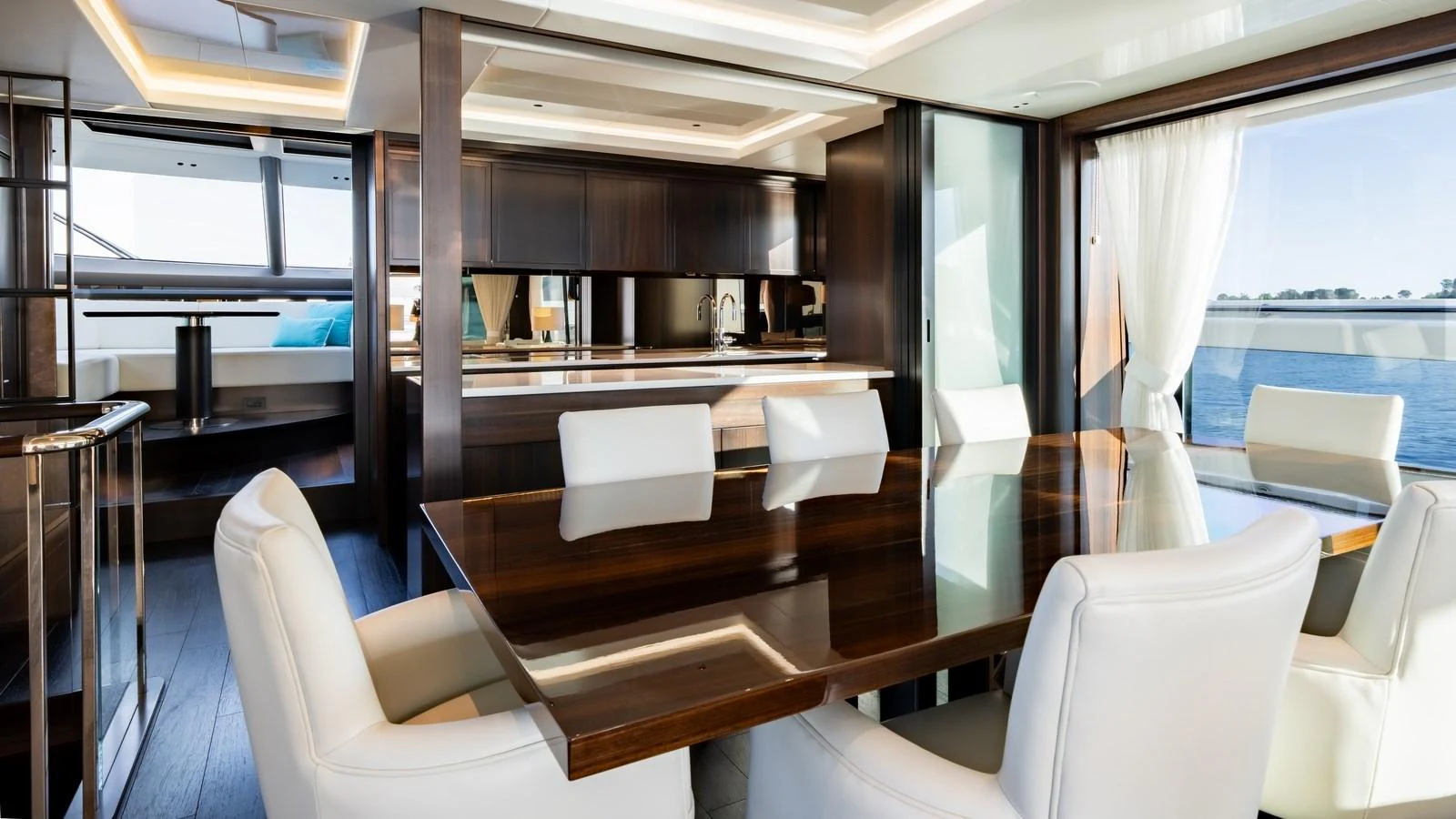 The yacht's dining area features a sleek wooden table surrounded by plush white chairs, offering a luxurious setting for meals with a view of the sea. aboard TRIPLE EIGHT Yacht for Sale