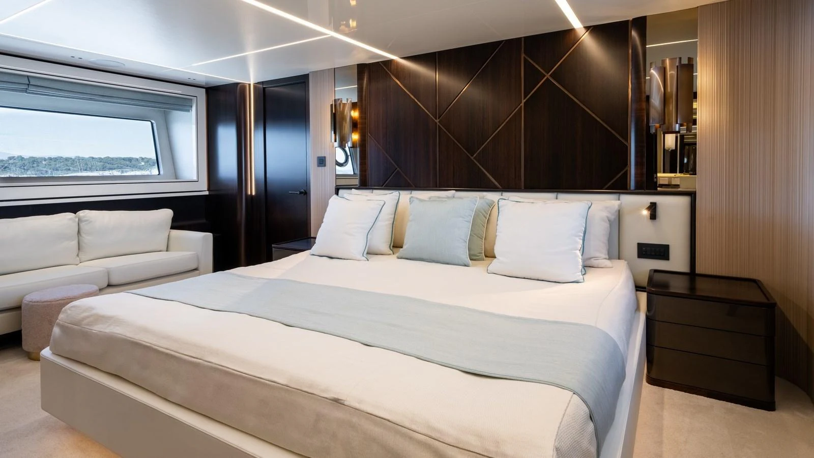 The master stateroom features a luxurious bed with elegant wood paneling and a large window offering scenic views. aboard TRIPLE EIGHT Yacht for Sale