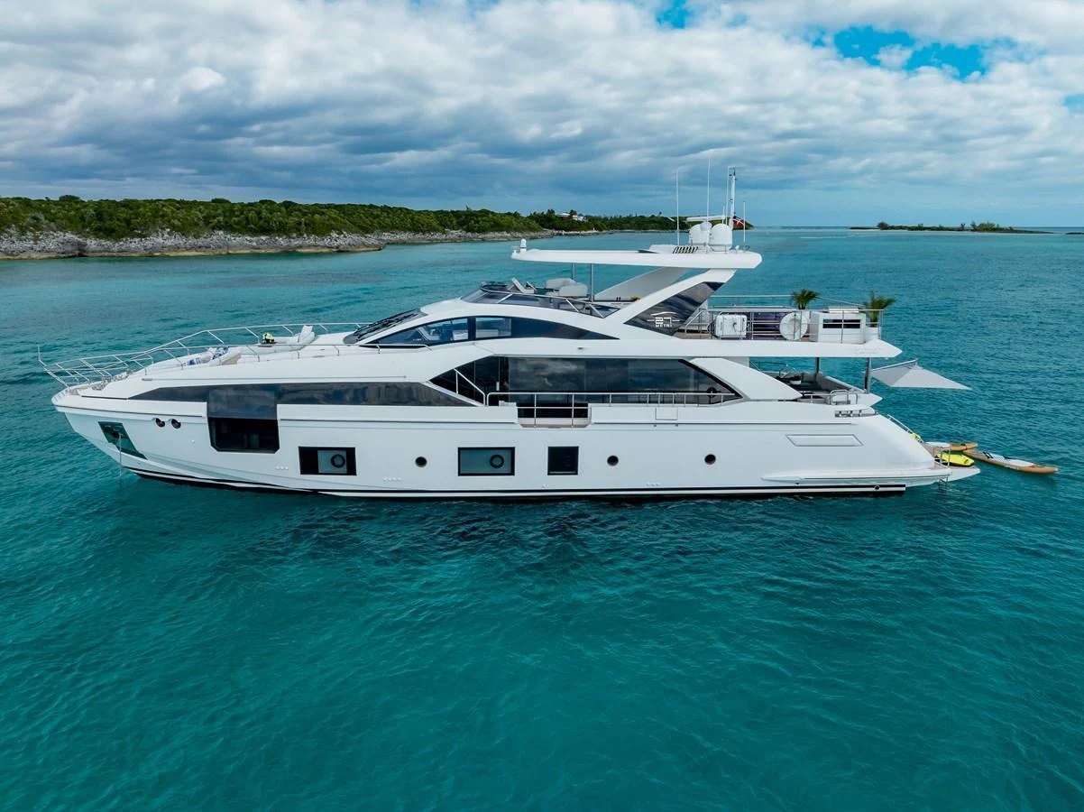 A sleek and modern yacht cruising in clear blue waters under a partly cloudy sky. aboard PIER PRESSURE Yacht for Sale