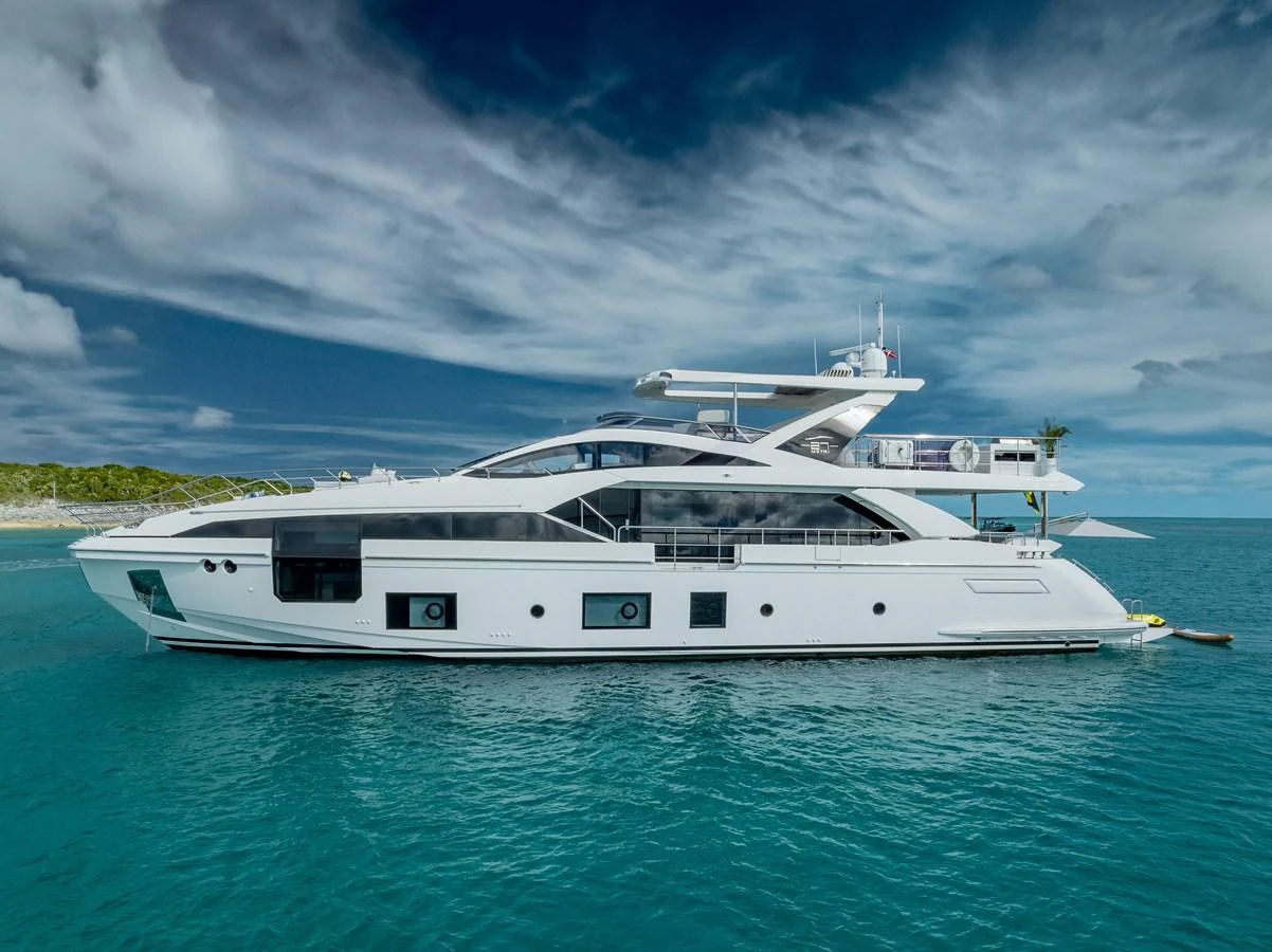 A sleek and modern yacht glides gracefully on calm turquoise waters under a partly cloudy sky. aboard PIER PRESSURE Yacht for Sale
