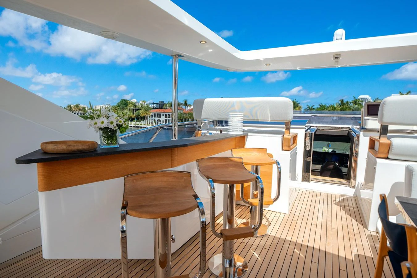 The flybridge features a stylish bar area with wooden stools and a sleek countertop, perfect for enjoying the view. aboard PIER PRESSURE Yacht for Sale