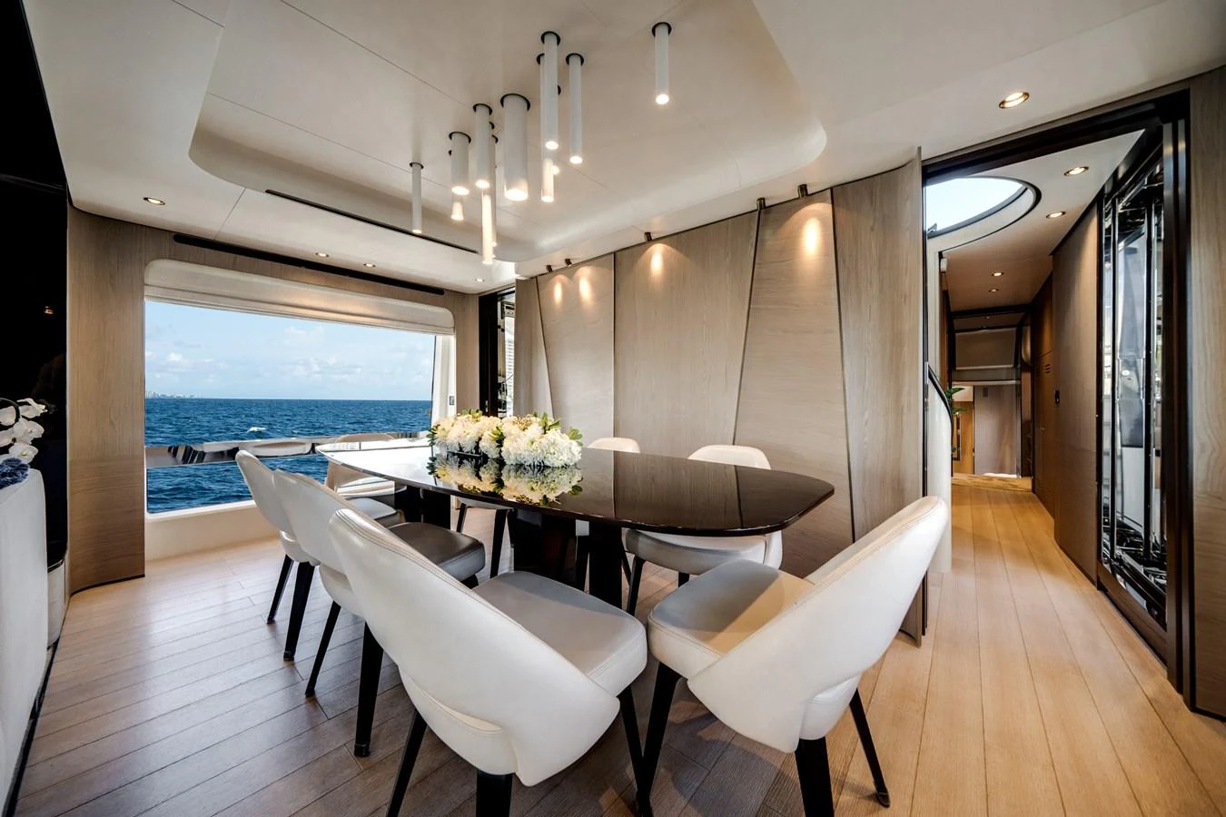 The yacht's dining area features a sleek table surrounded by plush chairs, with a view of the ocean through large windows. aboard PIER PRESSURE Yacht for Sale