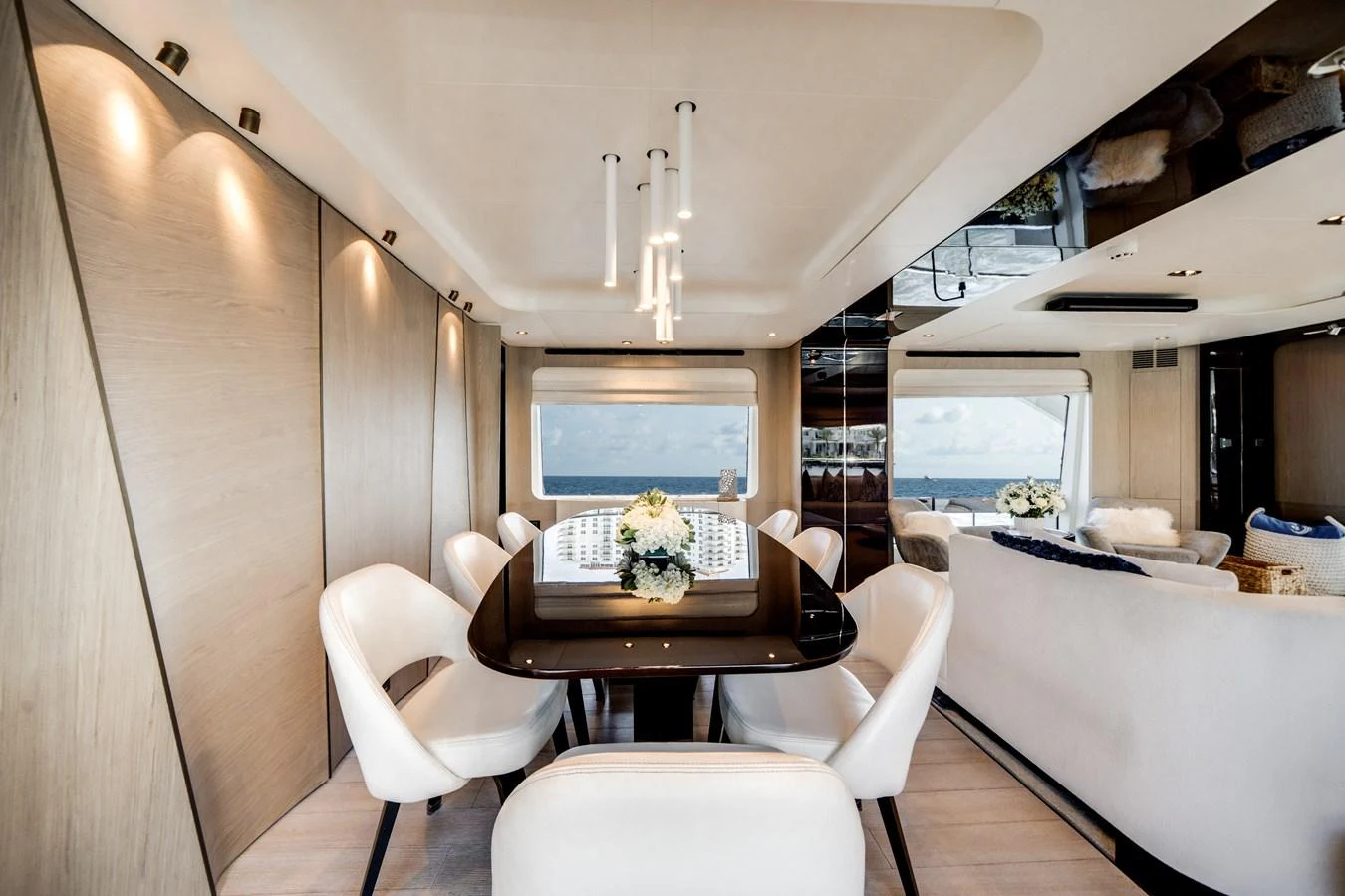 The yacht's dining area features a sleek table surrounded by plush chairs, with large windows providing a stunning ocean view. aboard PIER PRESSURE Yacht for Sale