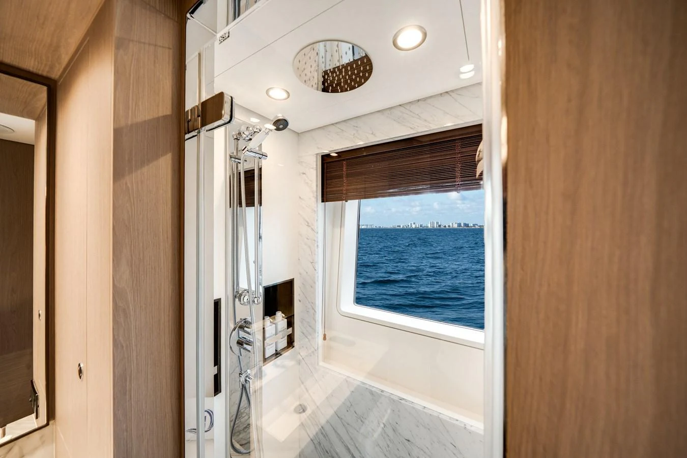 The yacht's bathroom features a modern shower with a stunning ocean view through a large window. aboard PIER PRESSURE Yacht for Sale