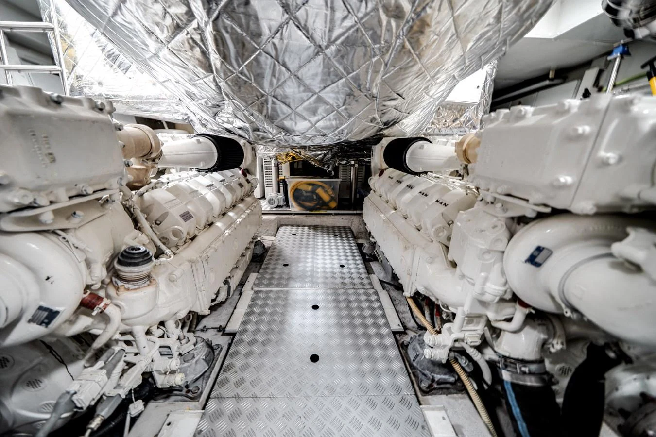 The image showcases the engine room with two large engines and metallic flooring. aboard PIER PRESSURE Yacht for Sale
