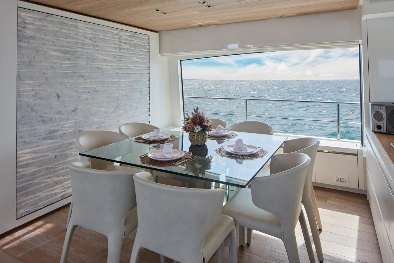 The yacht's dining area offers a stunning view of the sea through large windows, complemented by a modern glass table and elegant seating. aboard TNT LEISURE Yacht for Sale