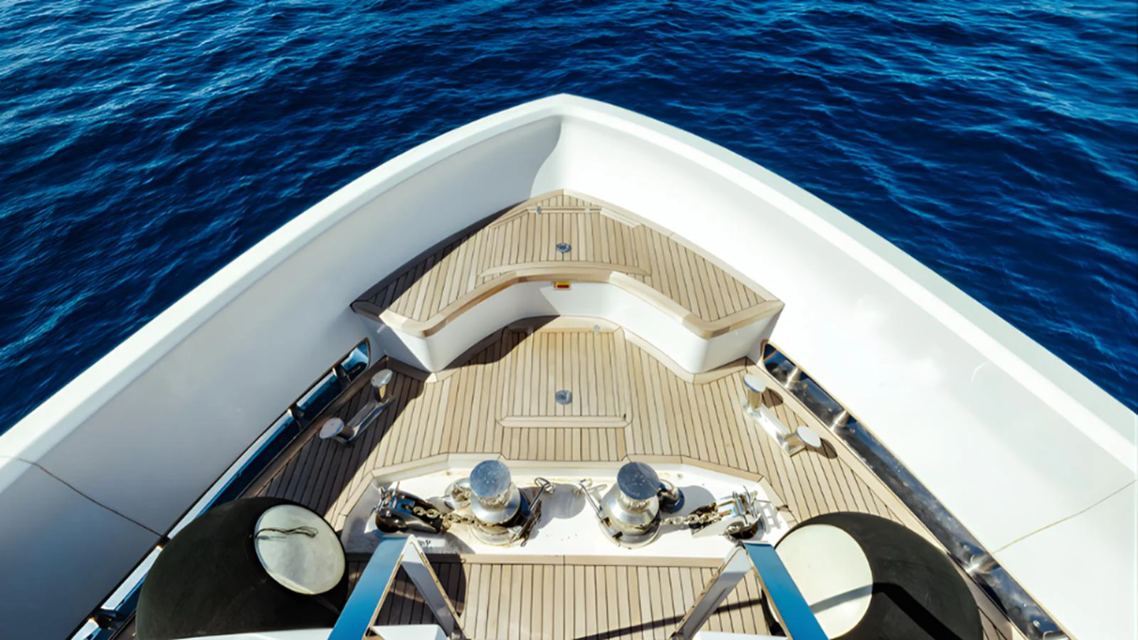 The image captures the bow of the yacht with a focus on the deck and anchor mechanisms against a backdrop of deep blue water. aboard MARCH SUNRISE Yacht for Sale
