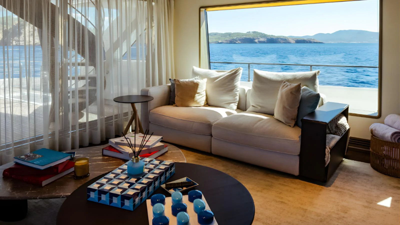 The yacht's interior features a cozy seating area with a stunning ocean view through large windows. aboard MARCH SUNRISE Yacht for Sale