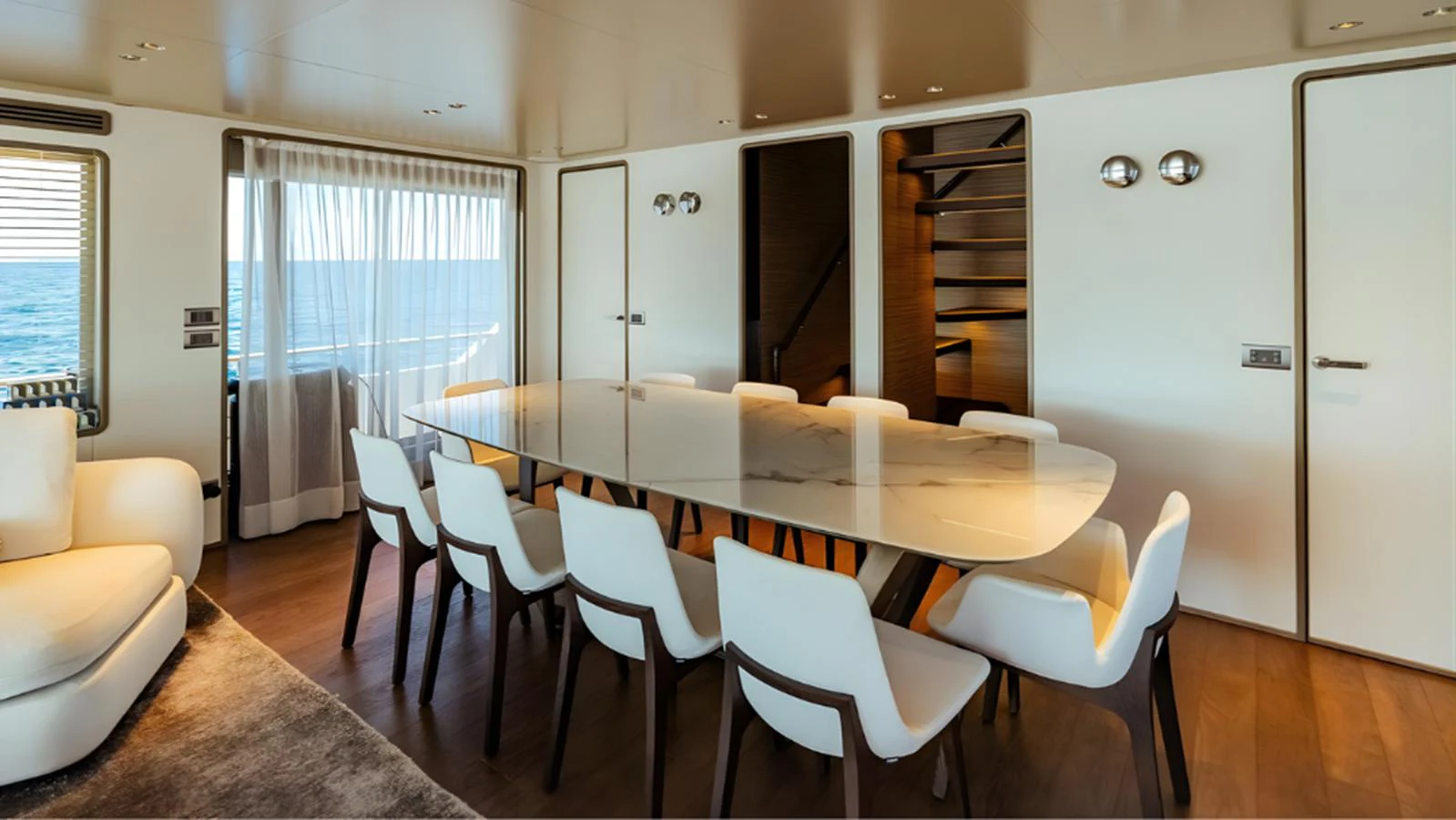 The yacht's dining area features a sleek, modern table surrounded by comfortable seating, with a view of the ocean through large windows. aboard MARCH SUNRISE Yacht for Sale
