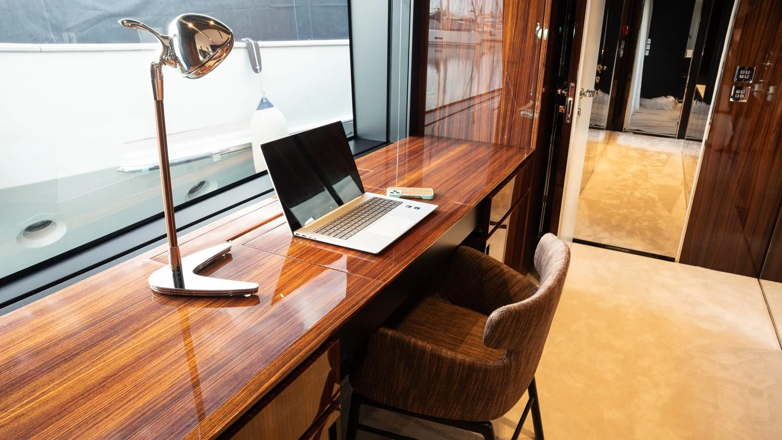 A luxurious yacht office with a sleek wooden desk, modern lamp, and comfortable chair. aboard ´LANTE Yacht for Sale