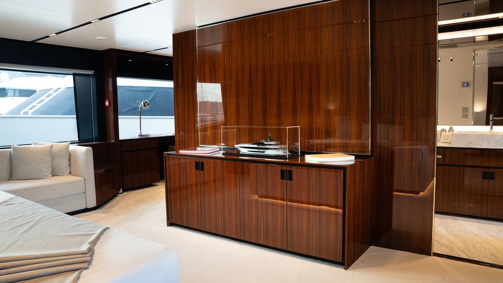 The yacht's interior features a sophisticated wooden cabinet with a model yacht displayed on top, complemented by modern furnishings. aboard ´LANTE Yacht for Sale