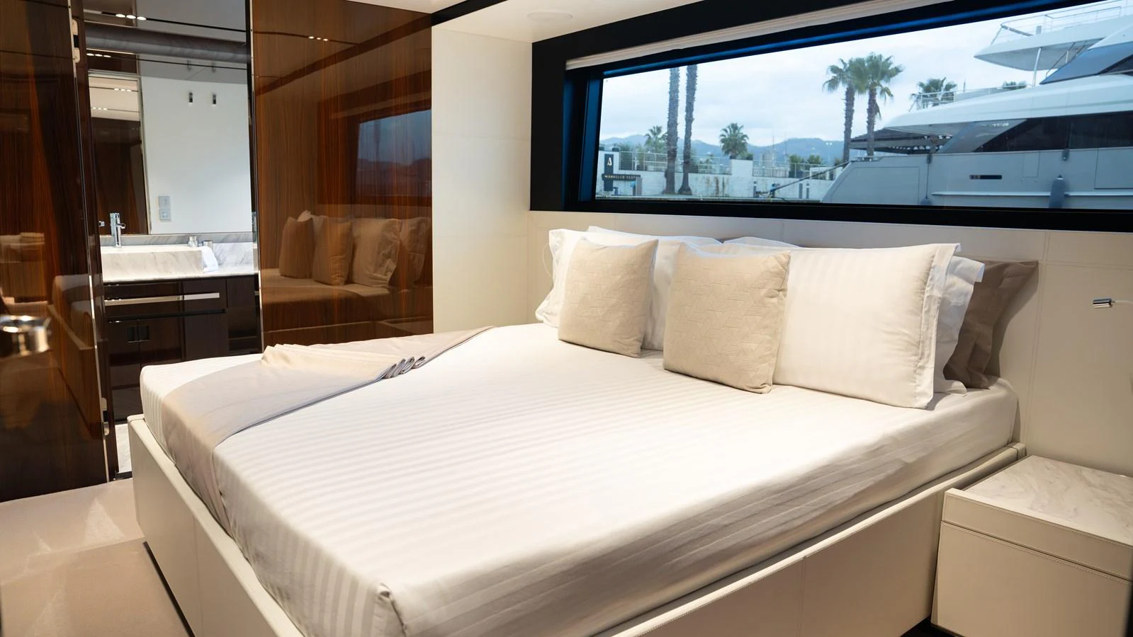A luxurious stateroom featuring a large bed with plush pillows and a view of the marina. aboard ´LANTE Yacht for Sale