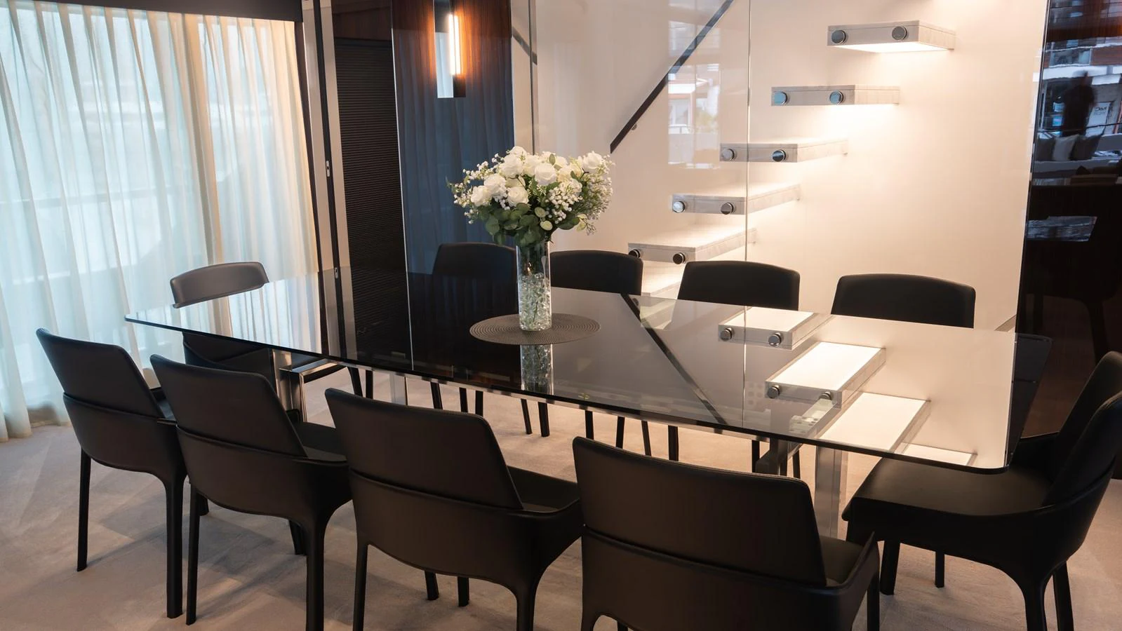 The yacht's dining area features a sleek glass table surrounded by modern black chairs, creating an elegant and inviting space. aboard ´LANTE Yacht for Sale