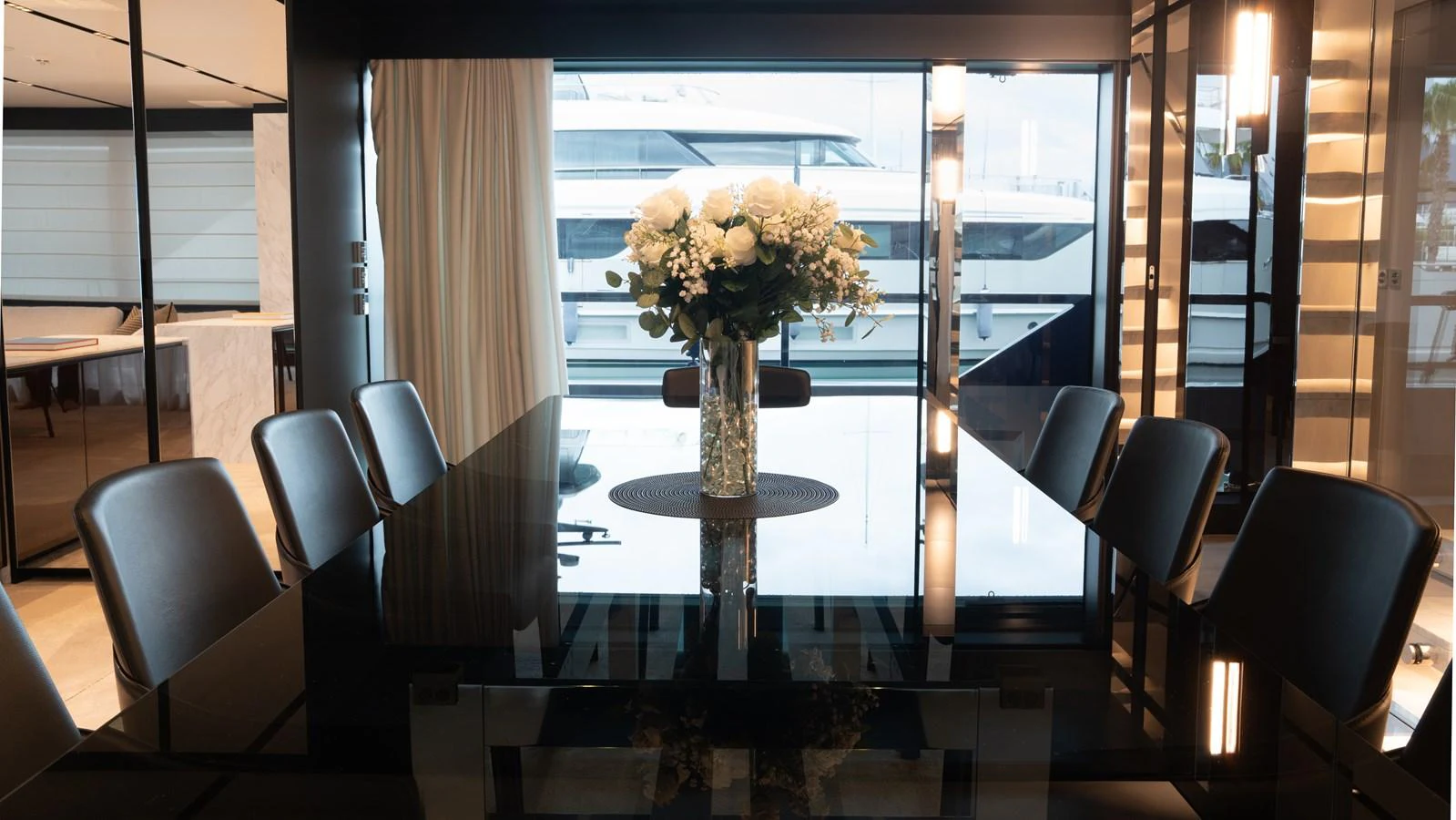 The elegant dining area features a sleek black table with a beautiful floral centerpiece, surrounded by modern chairs. aboard ´LANTE Yacht for Sale