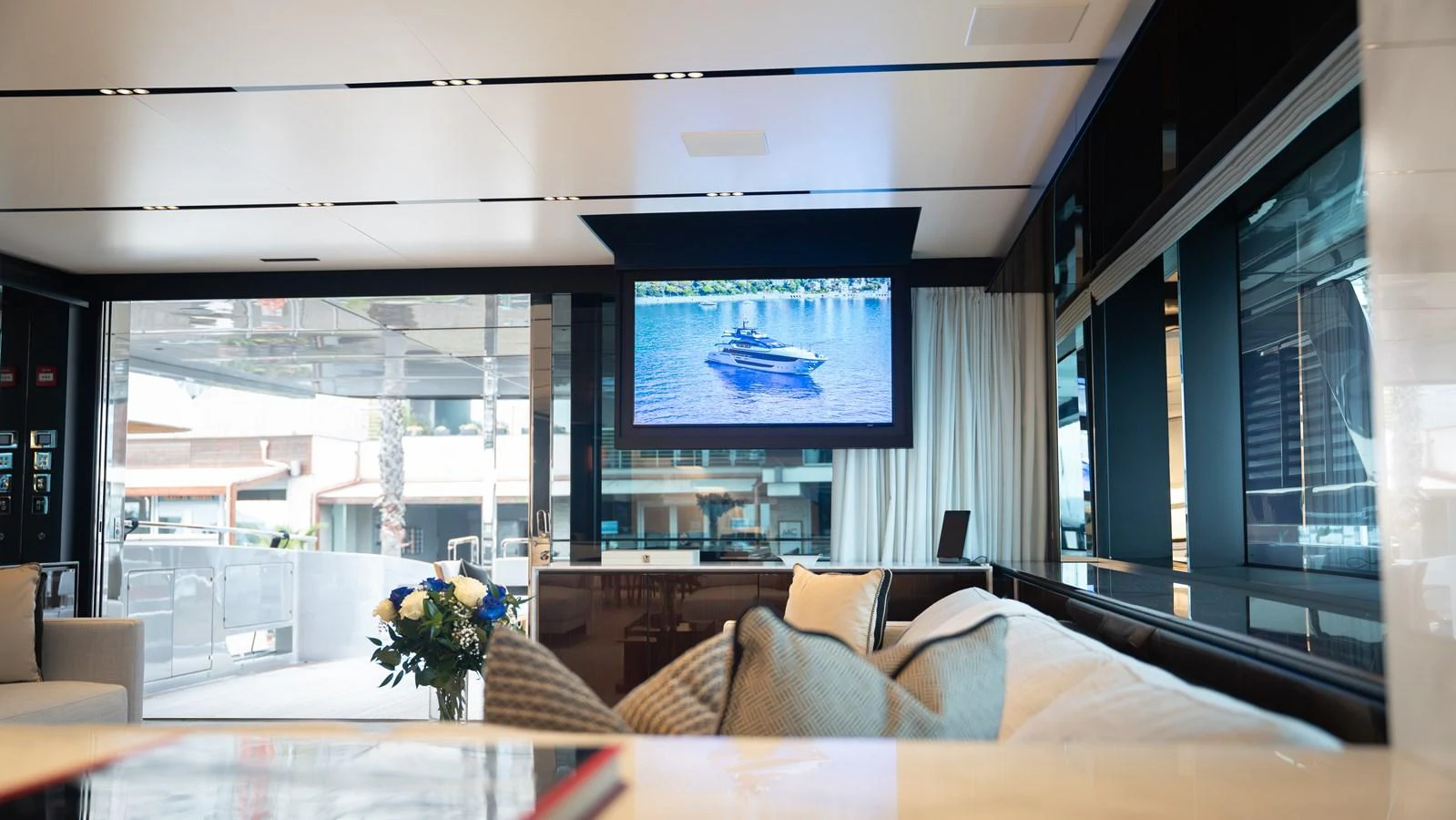 The yacht's interior features a comfortable seating area with a large window and a flat-screen TV displaying a scenic view. aboard ´LANTE Yacht for Sale