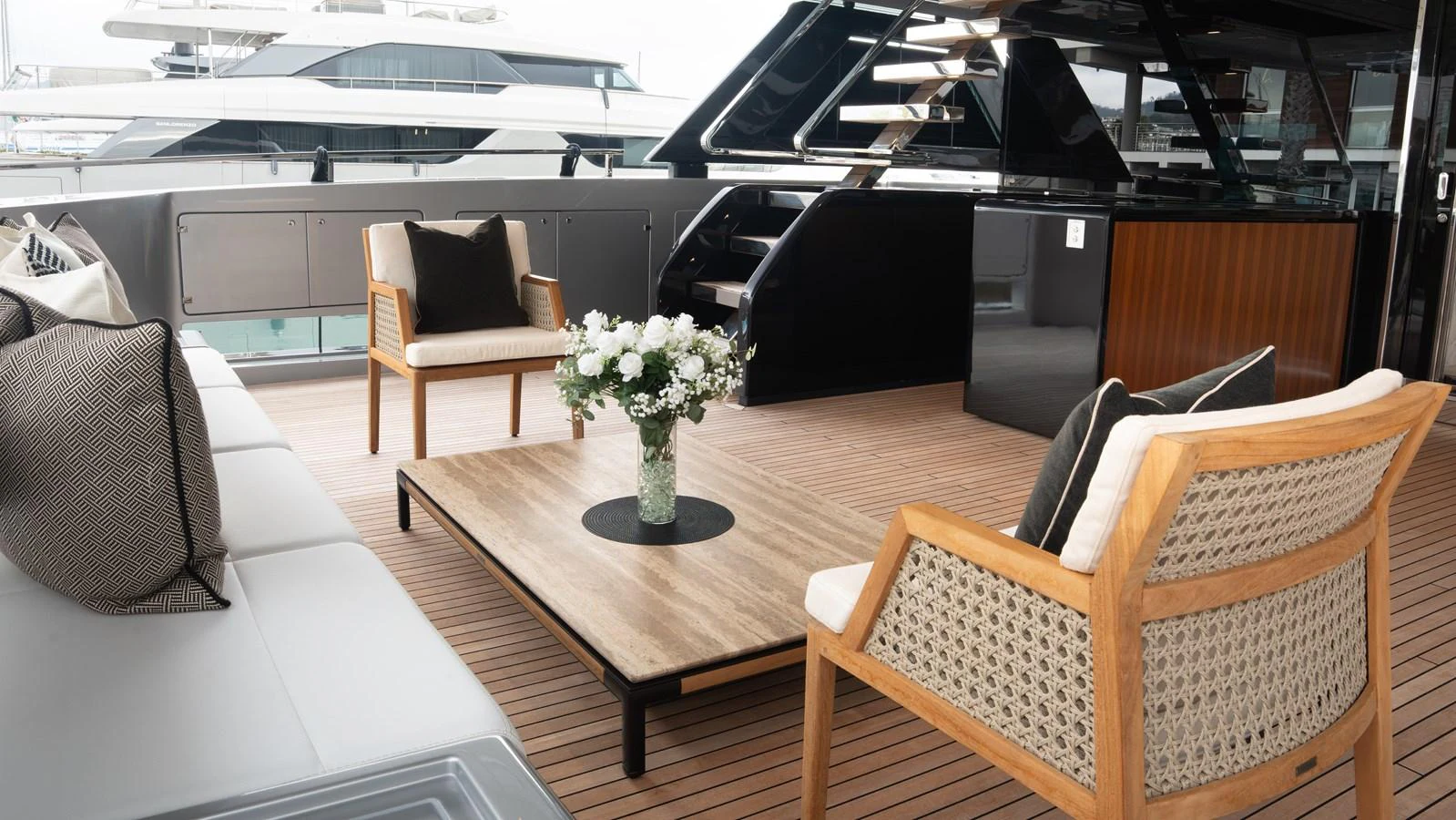 The aft deck features elegant seating with a wooden table and a beautiful floral centerpiece. aboard ´LANTE Yacht for Sale