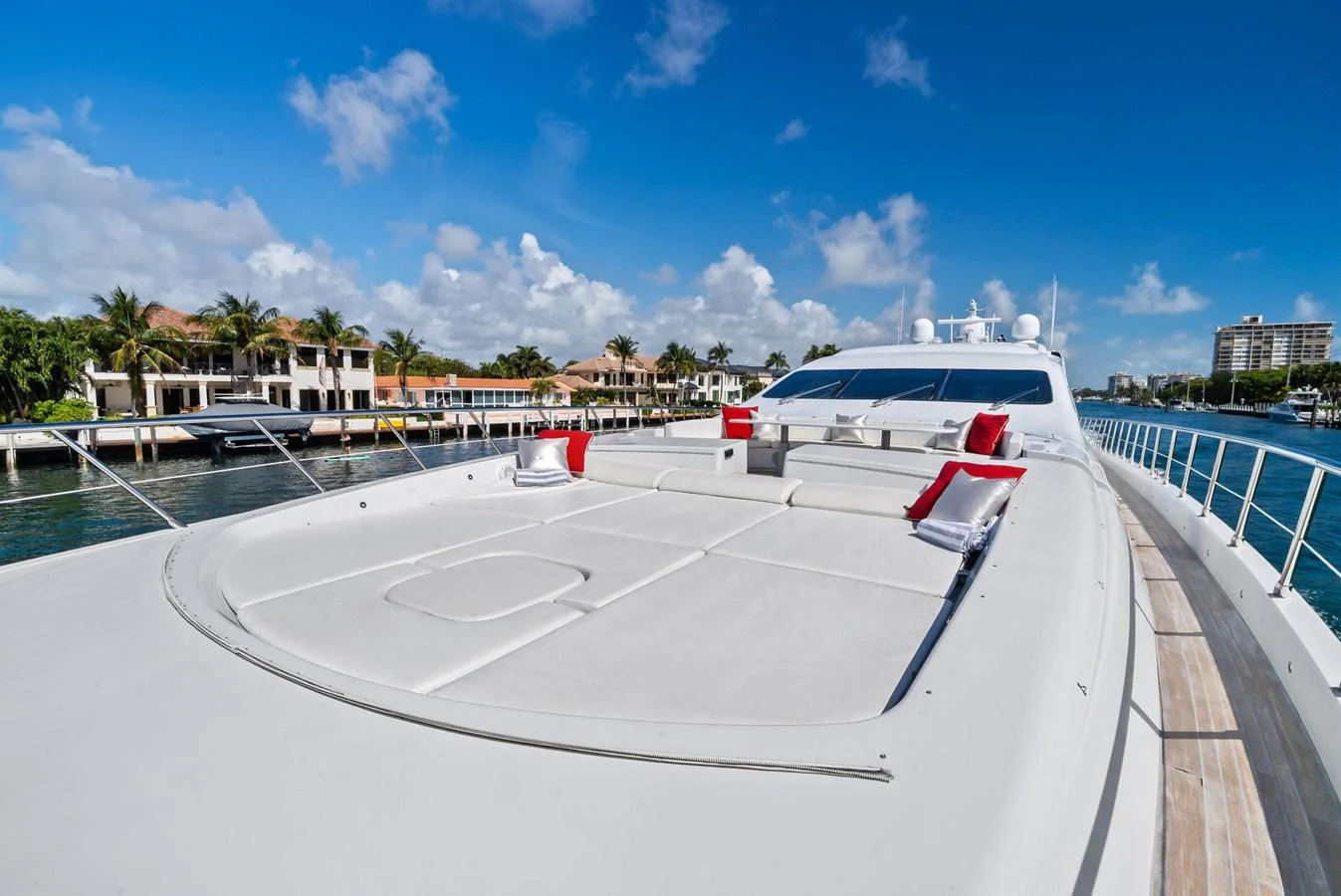The yacht's spacious foredeck offers a luxurious sunbathing area with plush red cushions and stunning waterfront views. aboard INCOGNITO Yacht for Sale