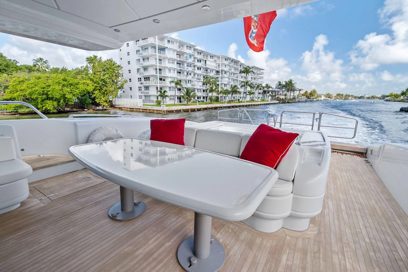 The aft deck features a spacious seating area with a sleek white table and vibrant red cushions, perfect for enjoying the view. aboard INCOGNITO Yacht for Sale
