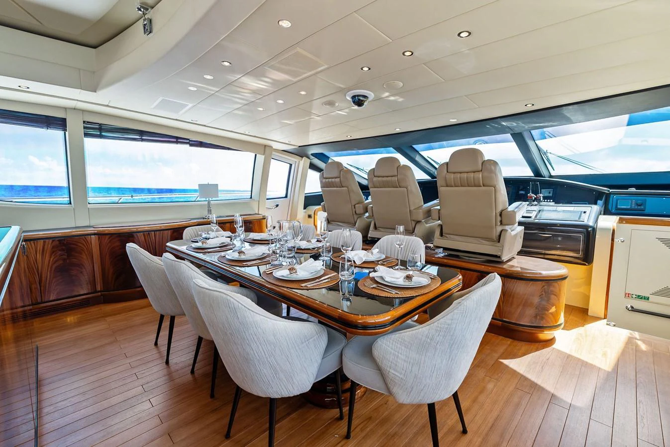 The yacht's dining area features a beautifully set table with plush seating and a view of the helm. aboard INCOGNITO Yacht for Sale