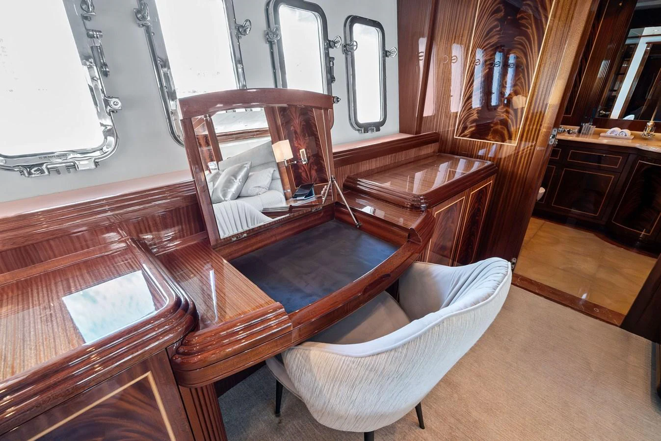 The yacht's vanity area features elegant wood finishes and a comfortable chair, creating a luxurious space for personal grooming. aboard INCOGNITO Yacht for Sale