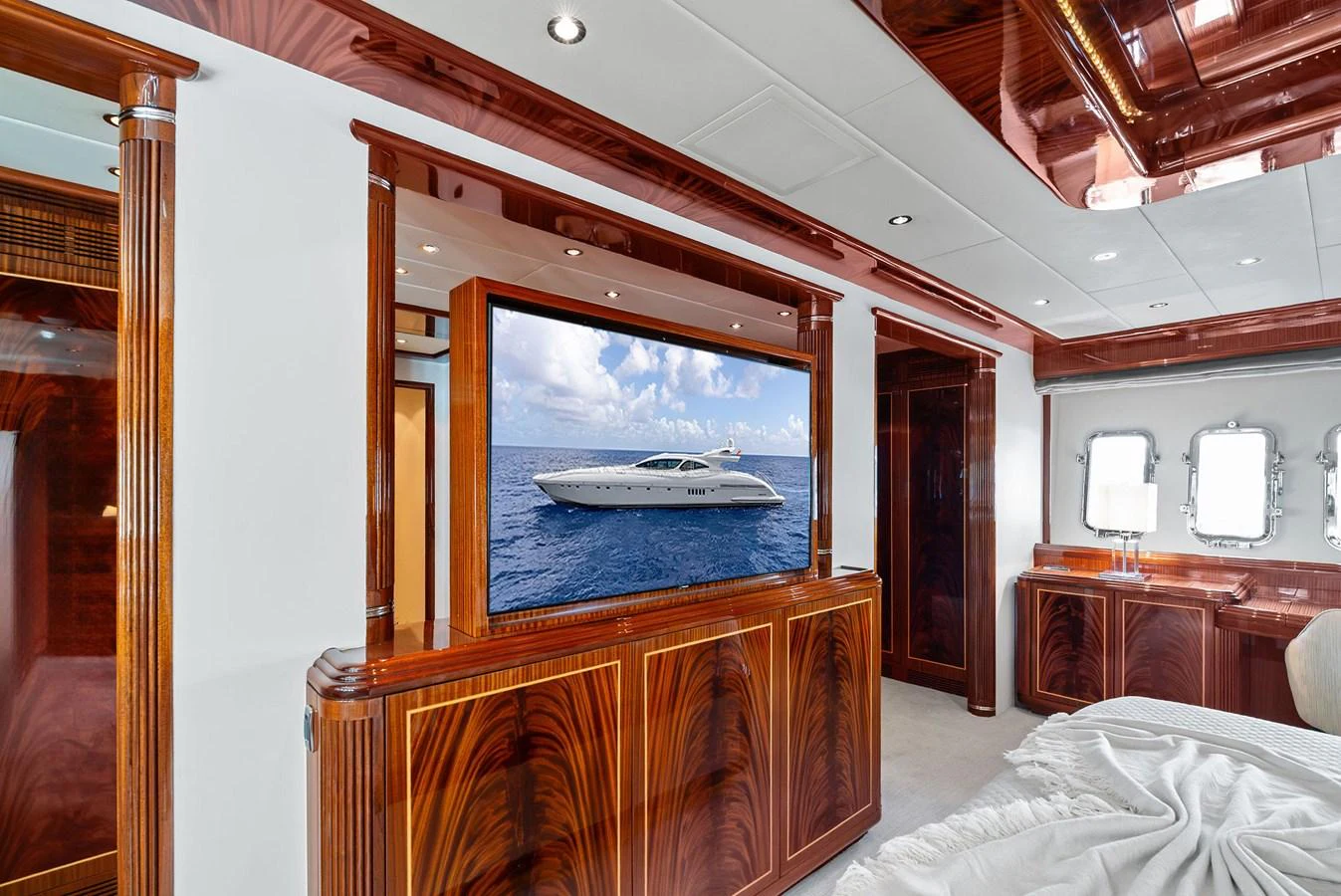 The stateroom features luxurious wood paneling and a large flat-screen TV displaying a yacht. aboard INCOGNITO Yacht for Sale