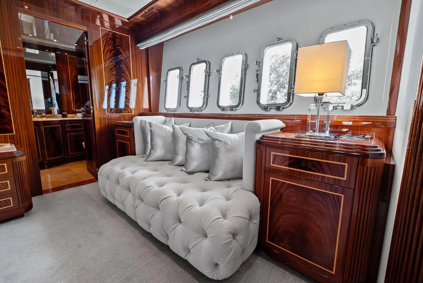 The yacht's interior features a plush, tufted sofa with elegant wooden cabinetry and large windows providing ample natural light. aboard INCOGNITO Yacht for Sale