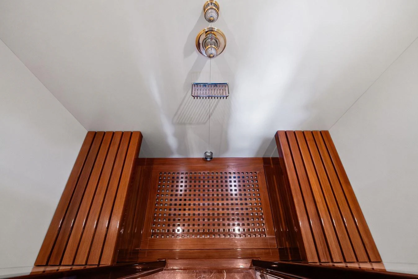 A luxurious yacht shower area with elegant wooden accents and a modern showerhead. aboard INCOGNITO Yacht for Sale