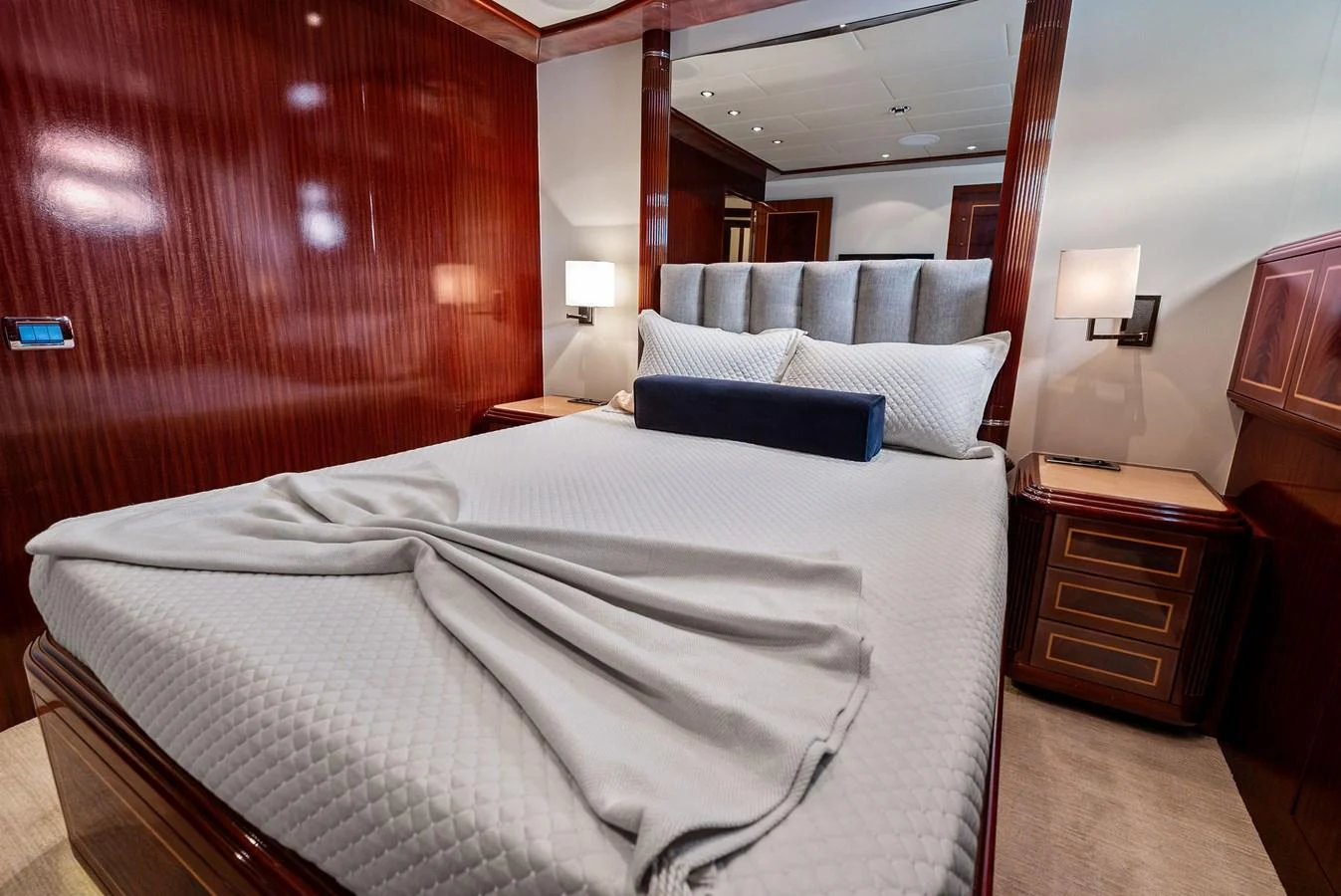 The stateroom features a luxurious bed with elegant wood paneling and ambient lighting. aboard INCOGNITO Yacht for Sale