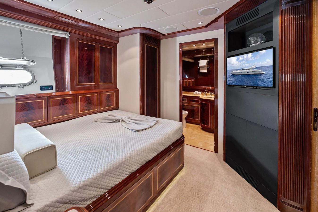 The stateroom features a luxurious bed, rich wood paneling, and a flat-screen TV. aboard INCOGNITO Yacht for Sale