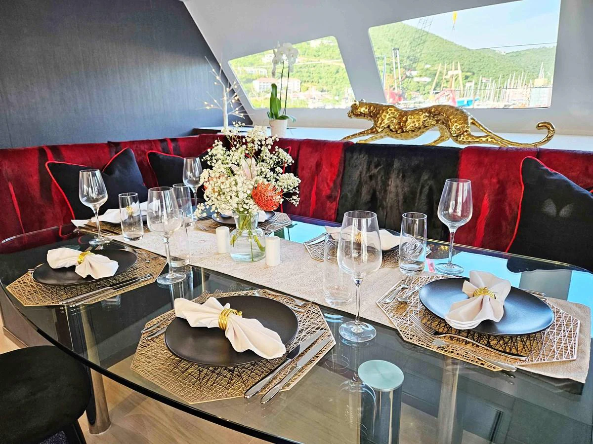 The yacht's dining area features a stylishly set table with elegant decor and a scenic view through the windows. aboard SILHOUETTE 800 Yacht for Sale