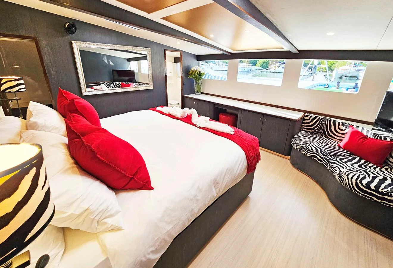 The master stateroom features a luxurious bed with vibrant red accents and ample natural light. aboard SILHOUETTE 800 Yacht for Sale