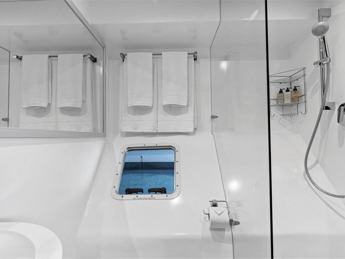 The yacht's bathroom features a sleek, modern design with a small window providing a view of the sea. aboard SILHOUETTE 800 Yacht for Sale