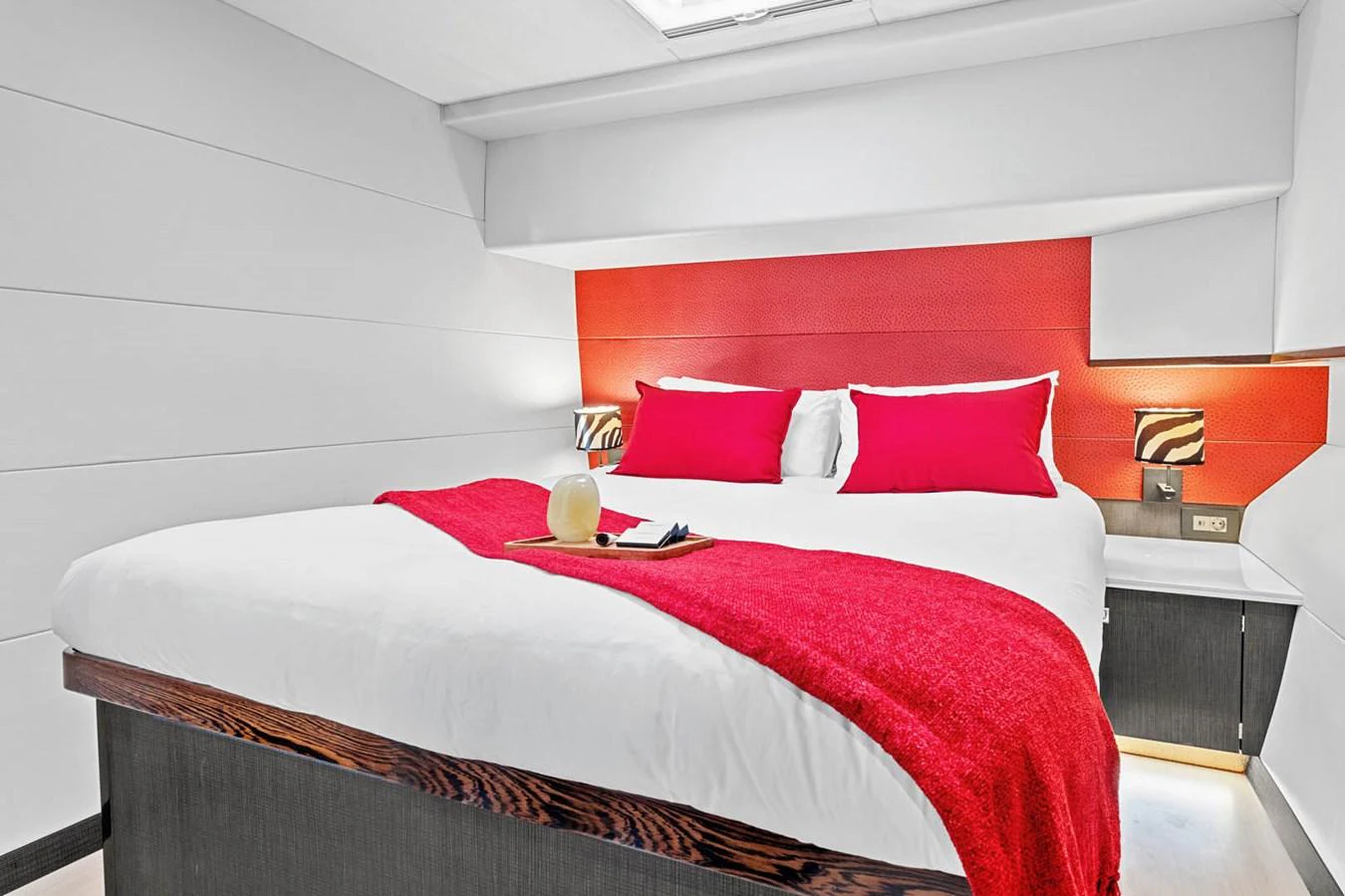 A luxurious stateroom featuring a large bed with vibrant red accents and modern lighting. aboard SILHOUETTE 800 Yacht for Sale