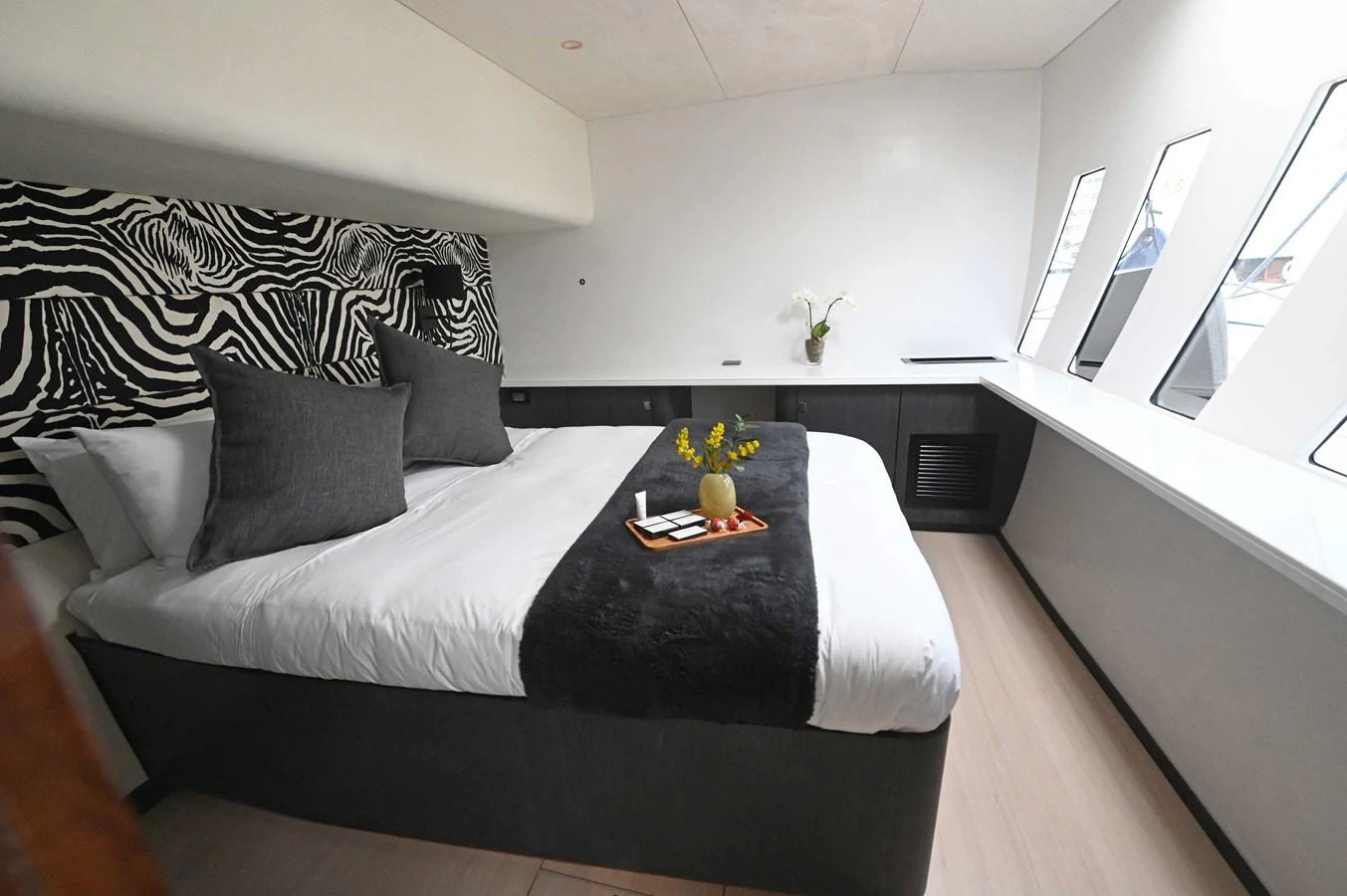 A luxurious stateroom featuring a large bed, modern decor, and ample natural light from the windows. aboard SILHOUETTE 800 Yacht for Sale