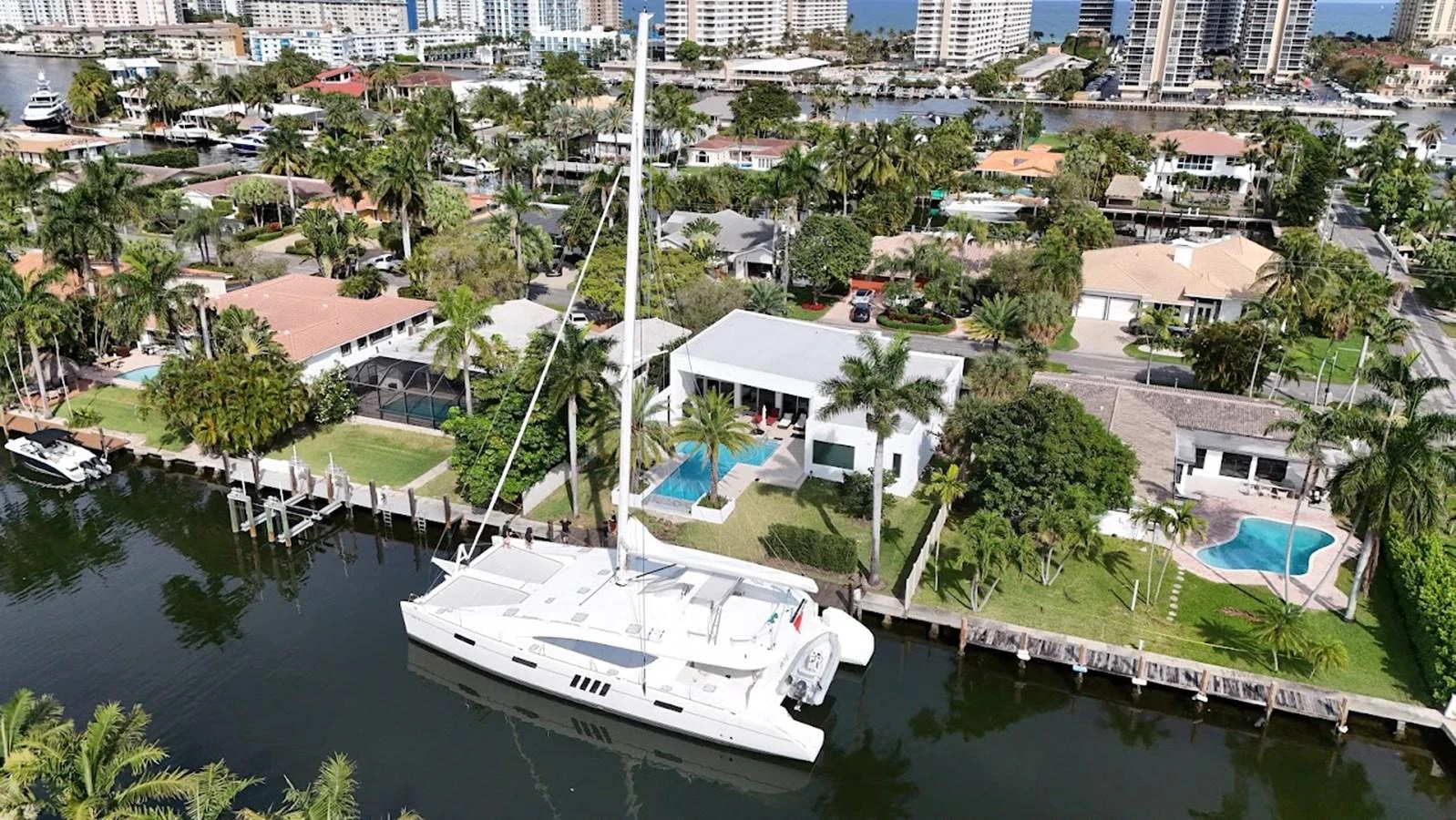 The yacht is docked in a serene residential canal, surrounded by luxurious waterfront homes and lush greenery. aboard SILHOUETTE 800 Yacht for Sale