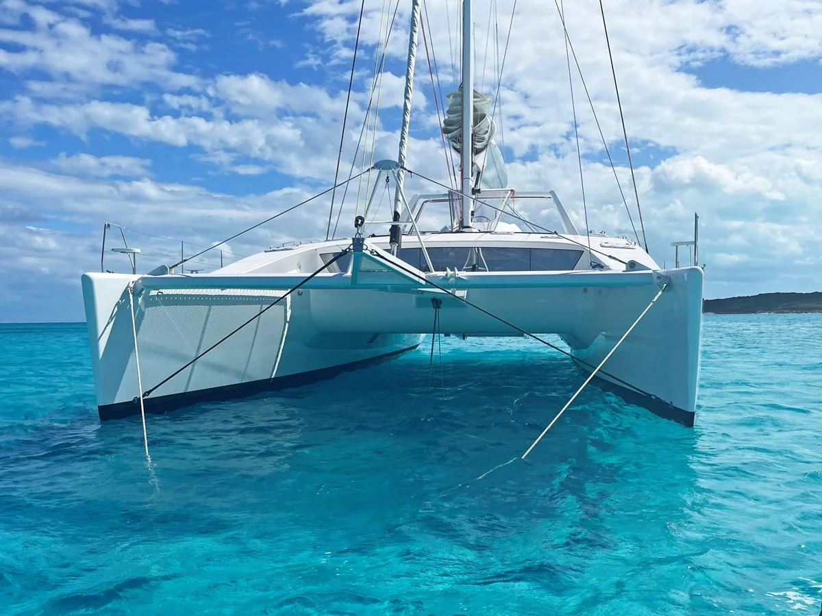 A sleek catamaran floats gracefully on crystal-clear turquoise waters under a partly cloudy sky. aboard SILHOUETTE 800 Yacht for Sale