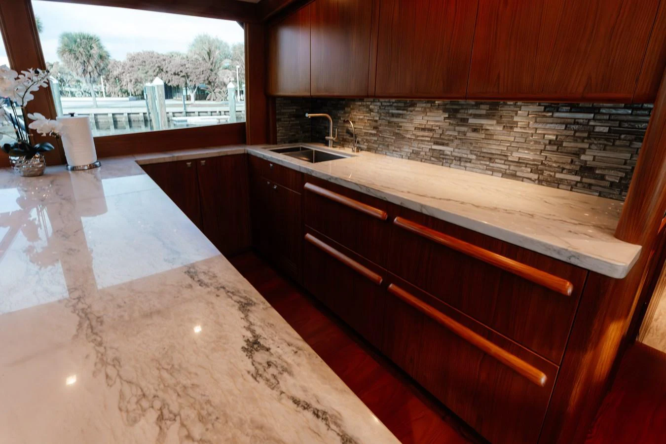 The yacht's galley features elegant wooden cabinetry and a sleek marble countertop. aboard NEVER SAY NEVER Yacht for Sale