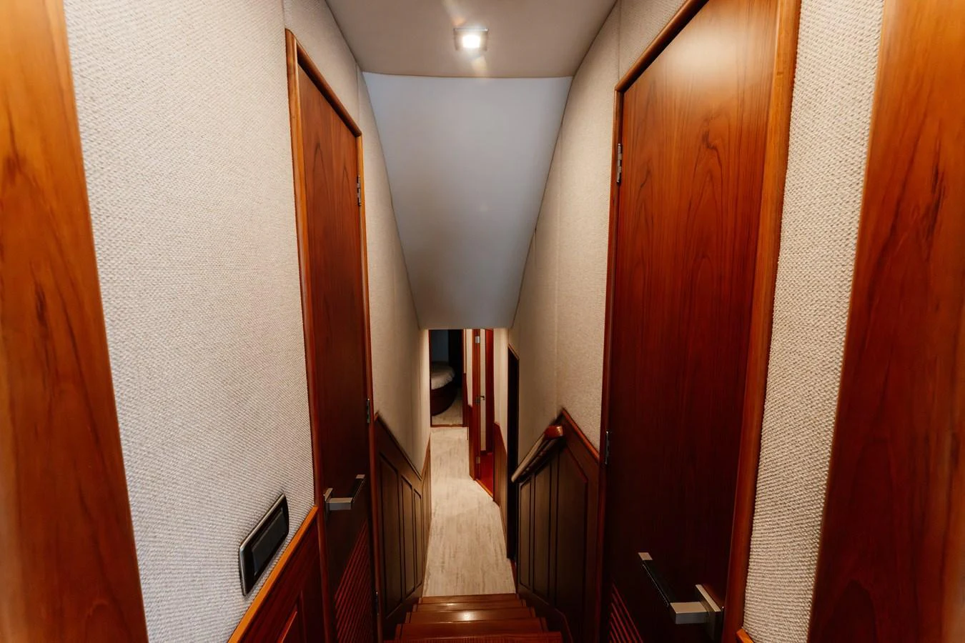A cozy interior hallway with wooden doors and soft lighting. aboard NEVER SAY NEVER Yacht for Sale