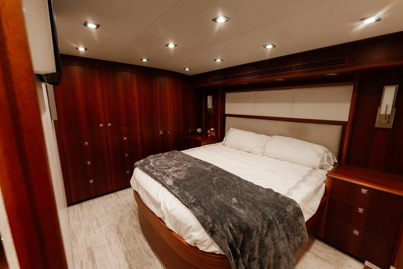 The stateroom features a luxurious bed with elegant wood finishes and modern lighting. aboard NEVER SAY NEVER Yacht for Sale