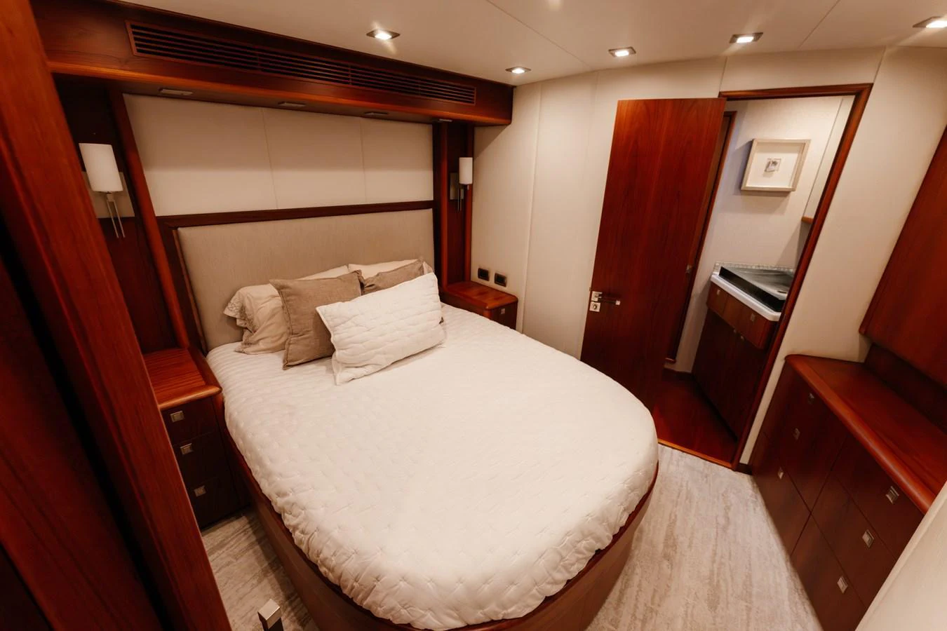 The stateroom features a cozy bed with elegant wood finishes and modern lighting. aboard NEVER SAY NEVER Yacht for Sale