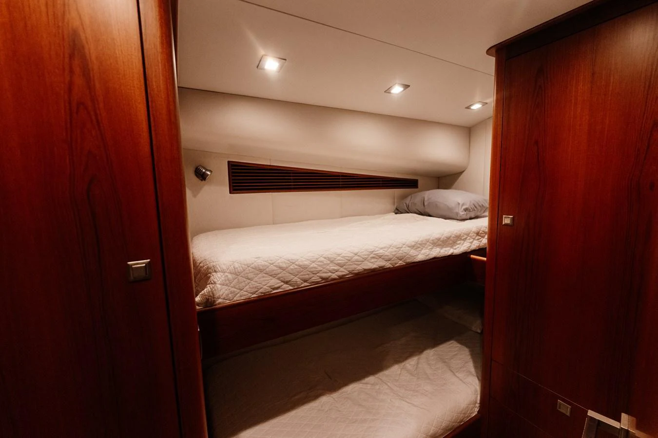 A cozy yacht cabin with warm wooden finishes and a comfortable bed. aboard NEVER SAY NEVER Yacht for Sale