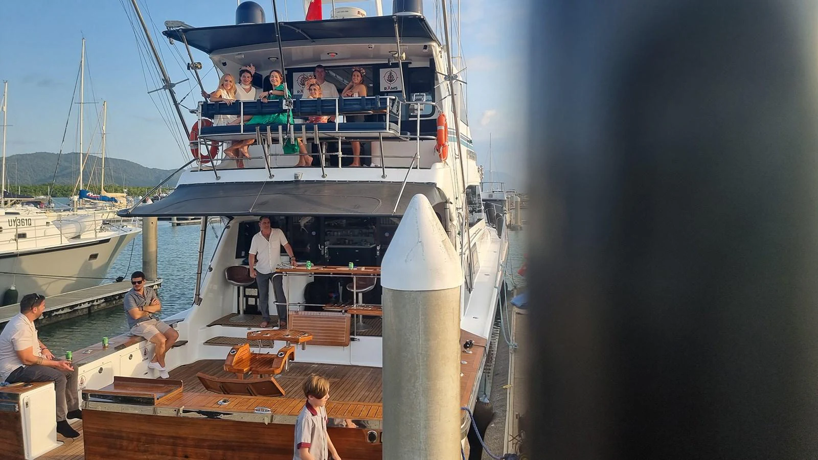 The yacht's aft deck is bustling with people enjoying the outdoor space while docked at the marina. aboard MEGISTI SPIRIT Yacht for Sale