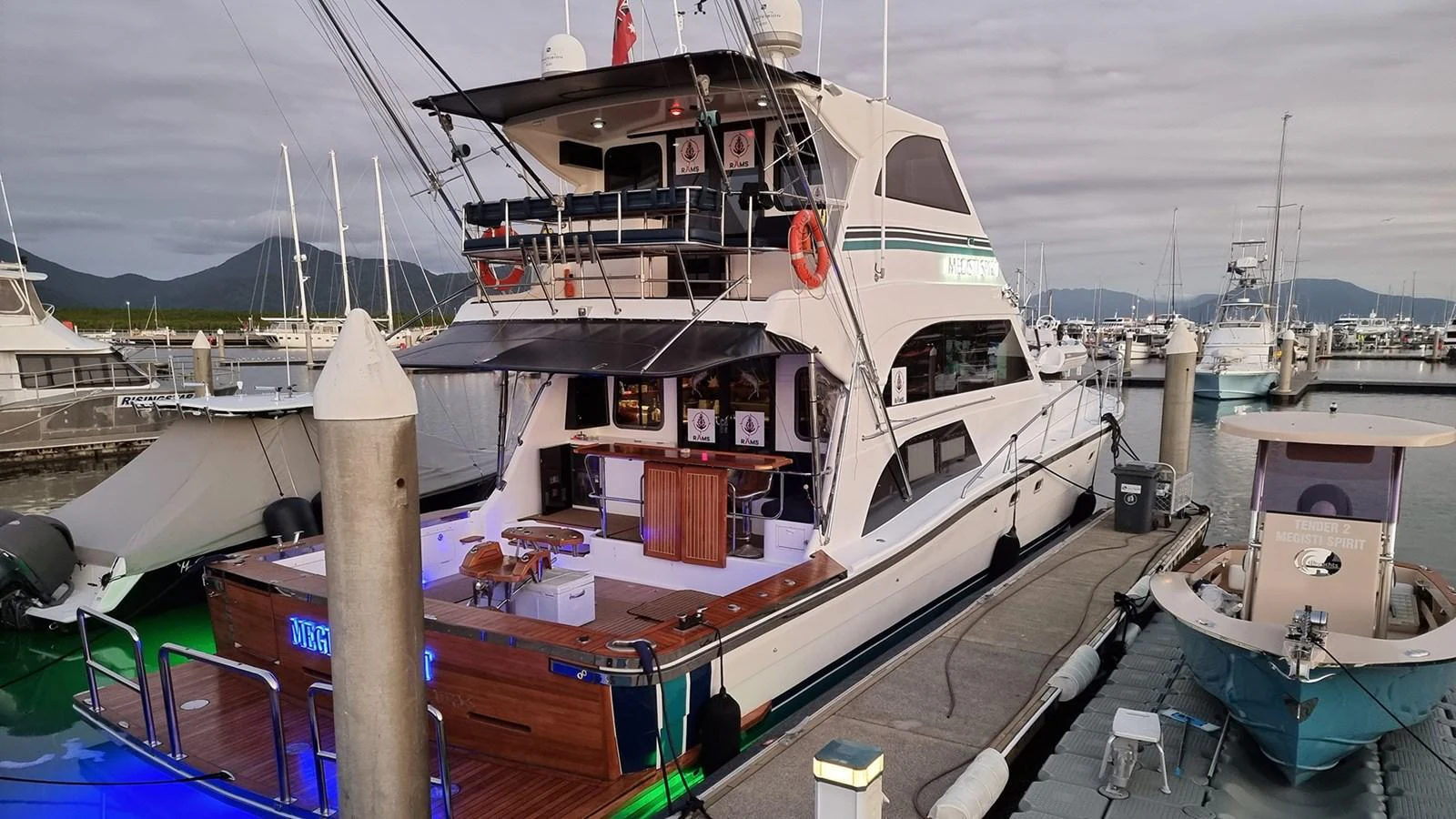 The yacht is docked at a marina, showcasing its spacious aft deck and multiple levels. aboard MEGISTI SPIRIT Yacht for Sale