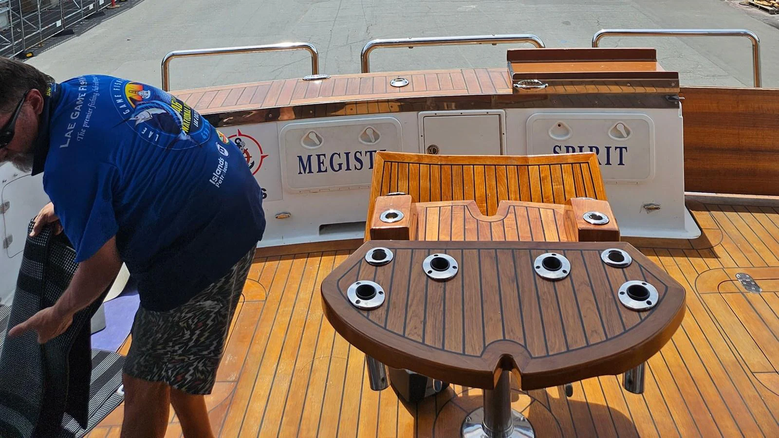 The aft deck features a wooden table with multiple cup holders and a comfortable seating area. aboard MEGISTI SPIRIT Yacht for Sale