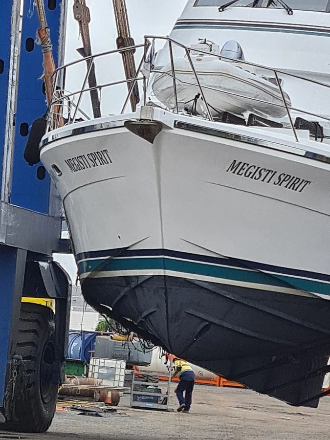 The yacht is being lifted out of the water, showcasing its bow and hull. aboard MEGISTI SPIRIT Yacht for Sale