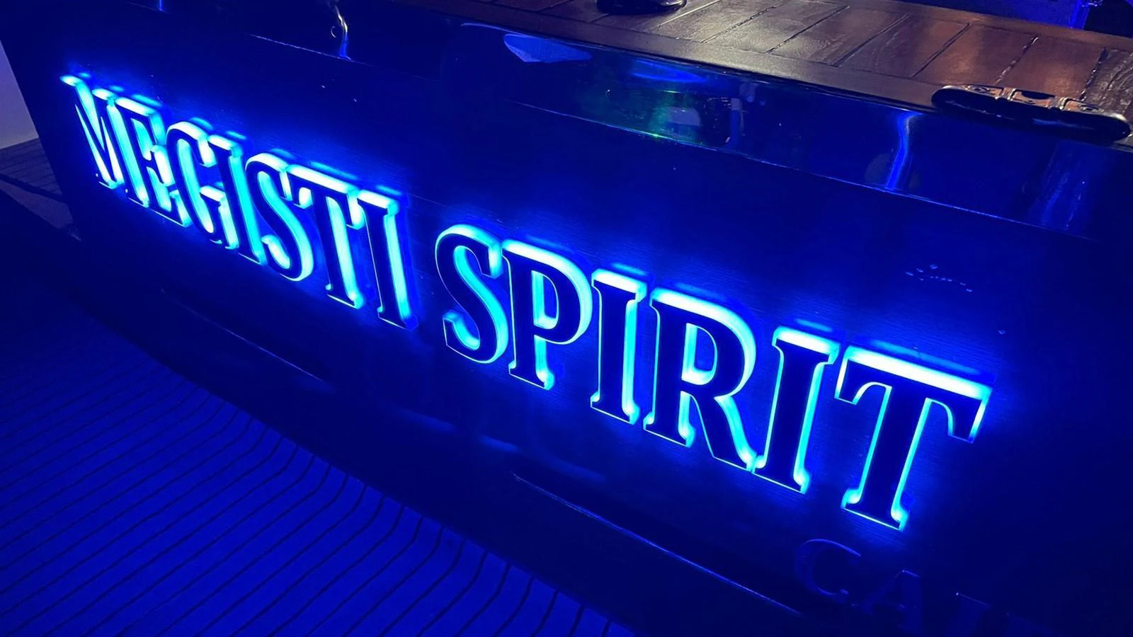 A close-up of a yacht's illuminated nameplate glowing in blue light. aboard MEGISTI SPIRIT Yacht for Sale