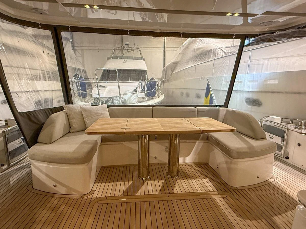 The aft deck features a comfortable seating area with a wooden table, perfect for socializing and dining. aboard PRINCESS 70 Yacht for Sale