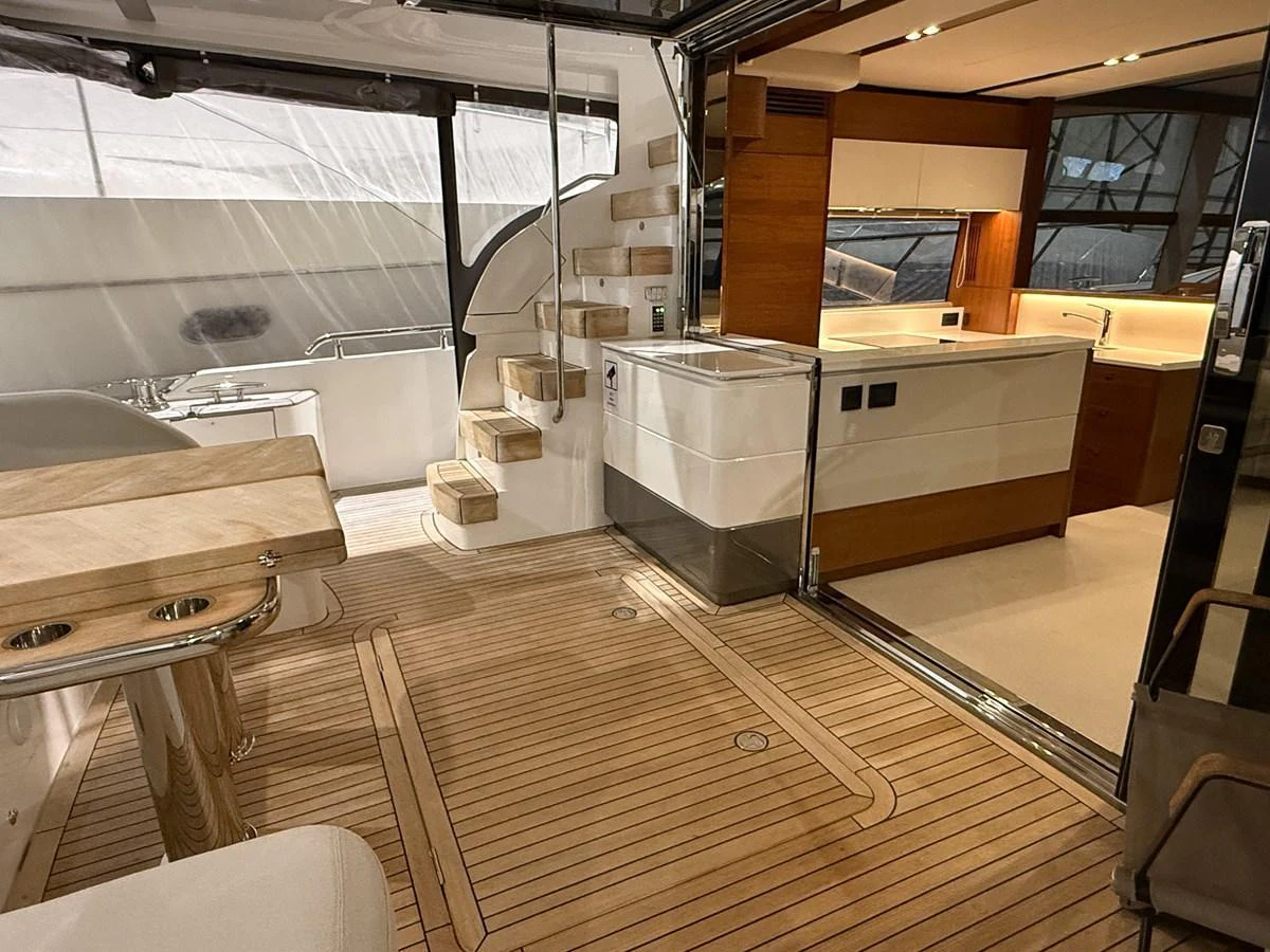 The image showcases a modern galley area with adjacent seating and wooden flooring. aboard PRINCESS 70 Yacht for Sale